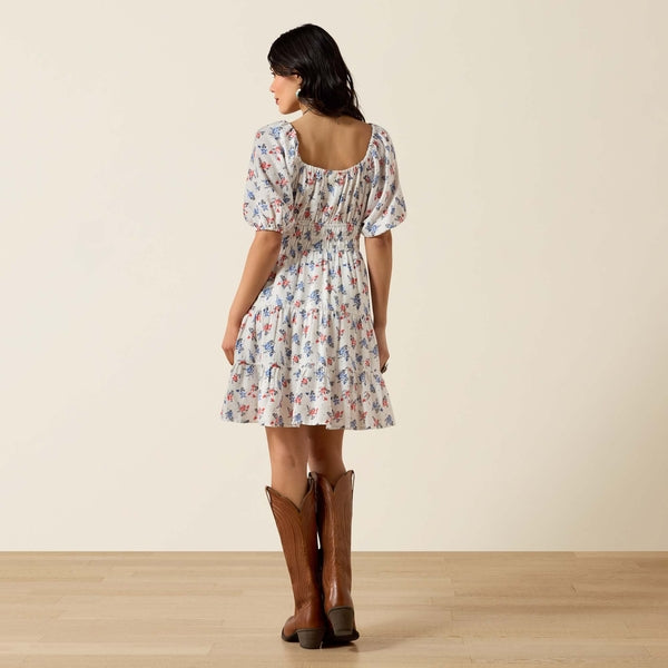 Woman wearing a floral dress and brown boots against a beige background