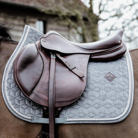 Close-up of a horse saddle with a quilted saddle pad on a horse.