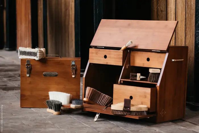 A deluxe show grooming box made of bamboo, featuring multiple compartments and gold snap closure, placed on a stable floor.