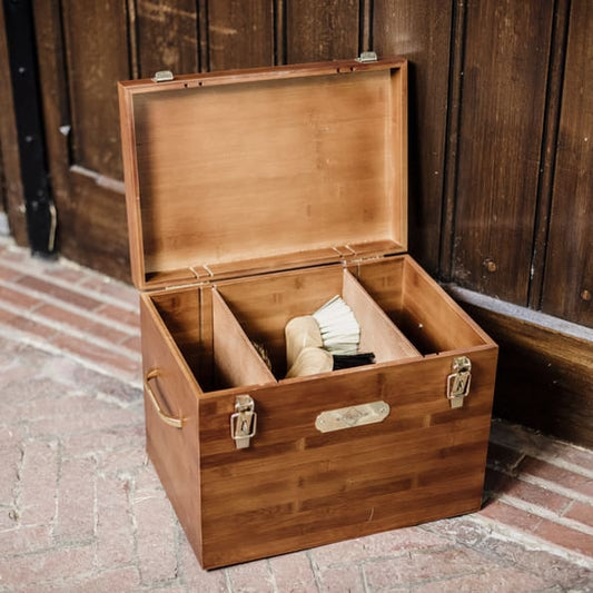 A deluxe stable grooming box made of bamboo, featuring multiple compartments and gold snap closure, in a stable yard.