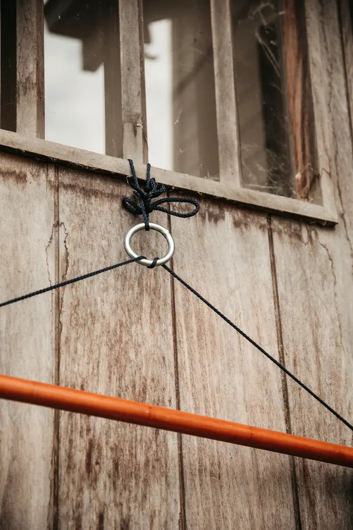 A navy bamboo saddle pad holder rack hanging against a wooden background, 