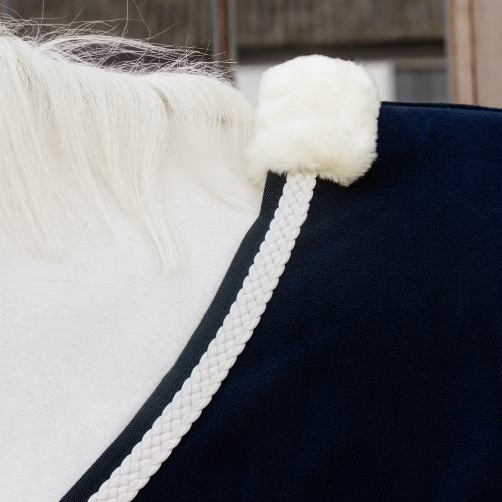 Close-up of a horse rug with white fluffy wither protection of the rug and braided detail.