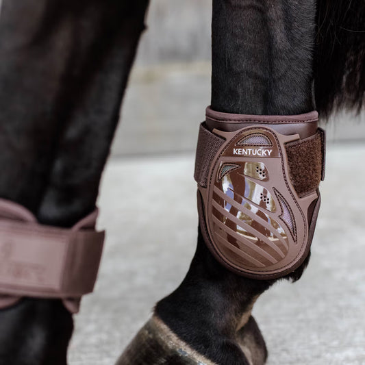 Horse leg with protective brown boot labeled 'Kentucky' on a blurred background