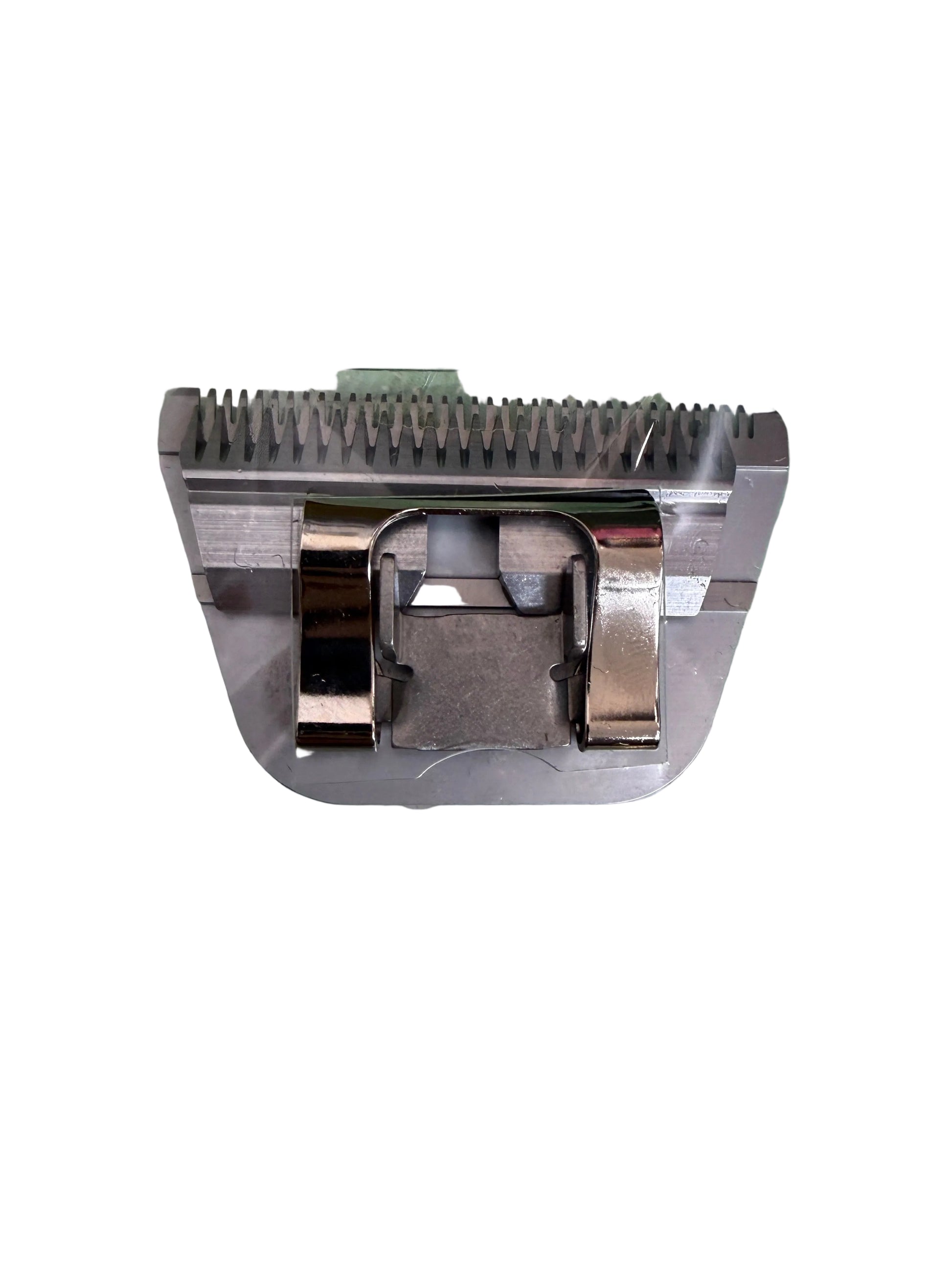 A metal electric clipper blade with a silver-colored guard, sealed inside a clear plastic protective sleeve, placed on a green and white polka dot surface.