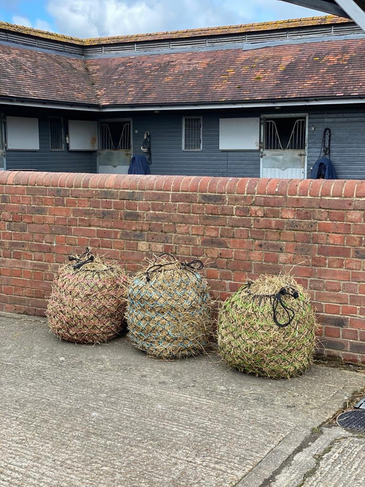 Three straw bales against a brick wall with a building in the background