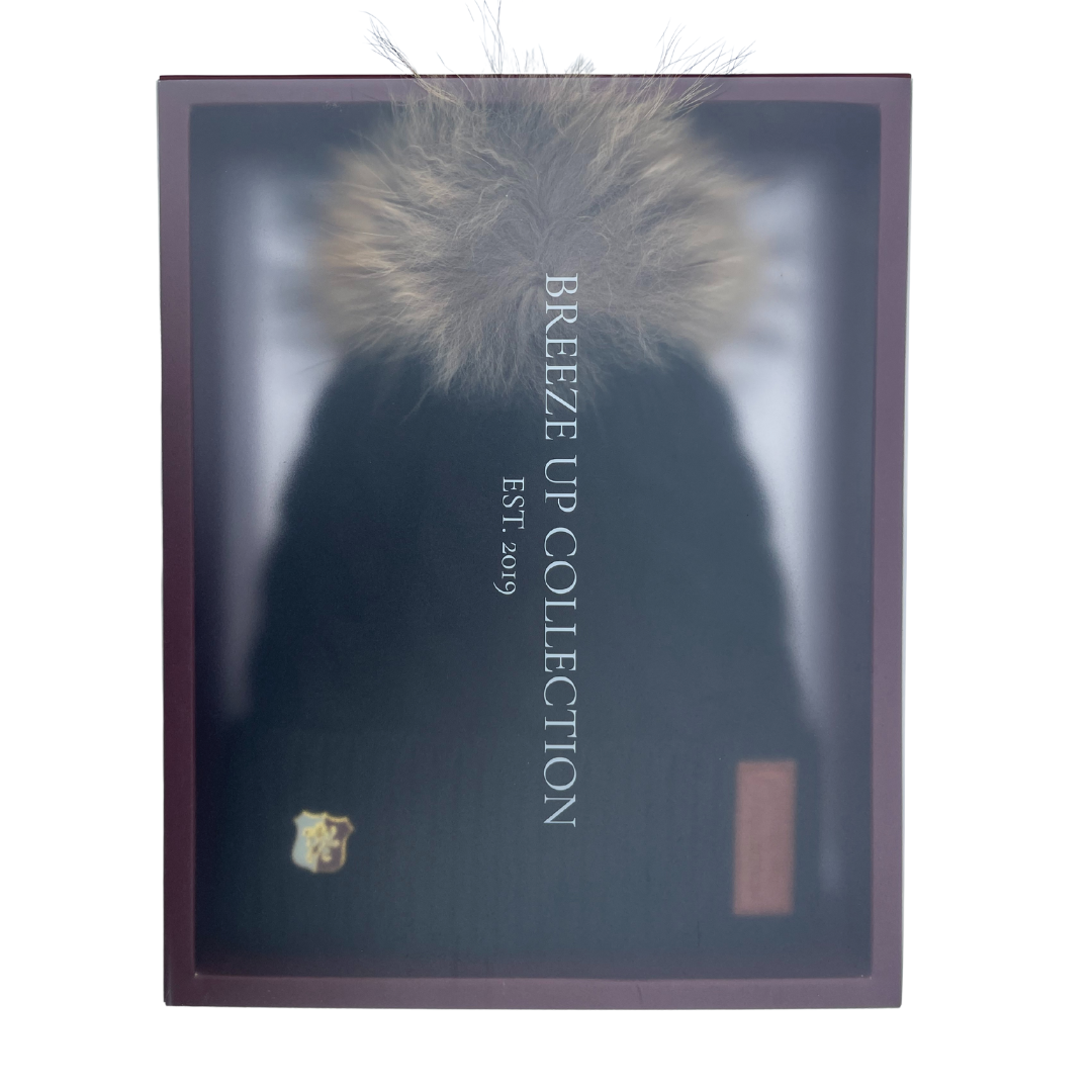 Dark blue beanie with fur pom-pom in a box labeled 'Breeze Up Collection'.