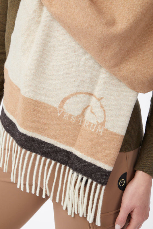 Beige and white scarf with fringe and 'Vestrum' logo worn by a person.