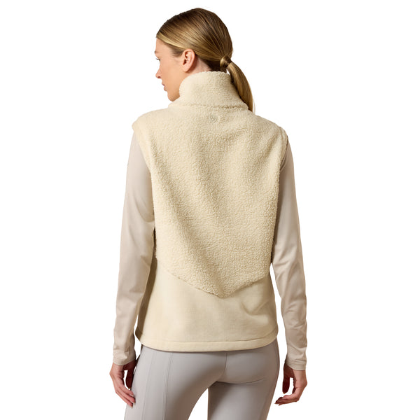 A woman shown from the back wearing a cream sherpa fleece vest over a beige long-sleeve shirt and gray leggings, against a plain white studio background.