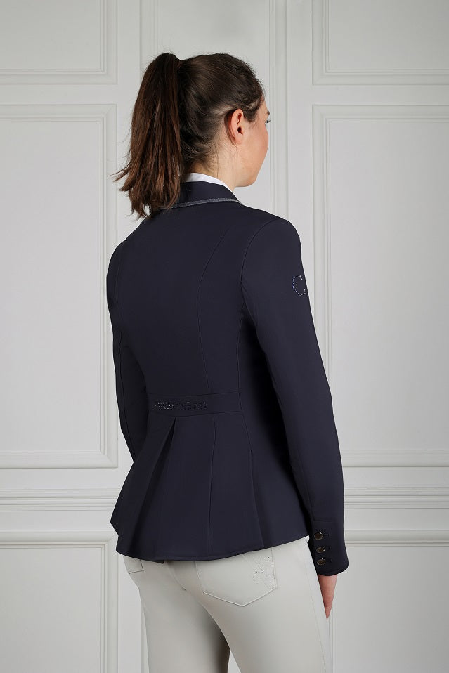 Person wearing a navy blazer against a light gray wall