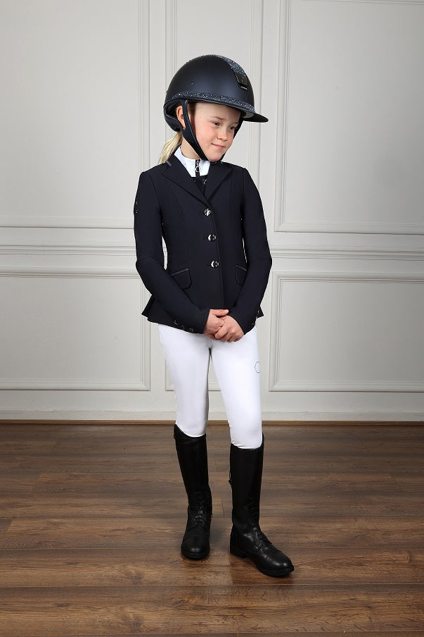 Child in equestrian attire with a helmet on a wooden floor.