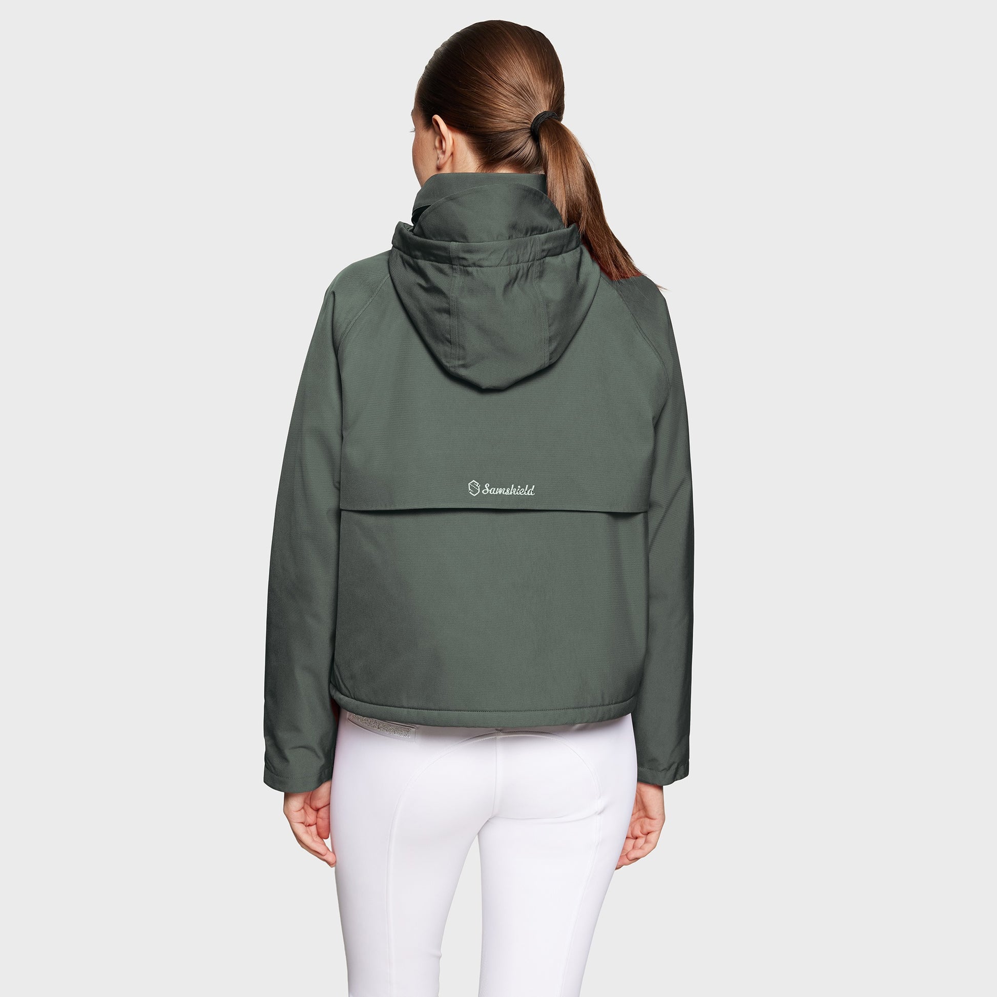 Person wearing a green jacket with a visible brand logo on a light gray background