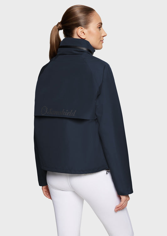 Woman wearing a navy jacket and white breeches on a beige background