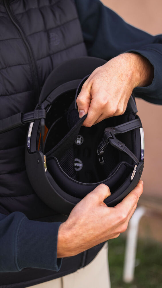 Person holding a black helmet with a blurred background