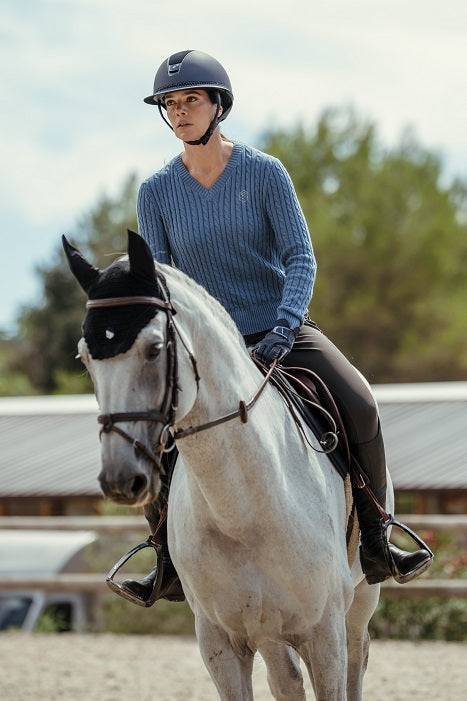 Person riding a white horse in an outdoor equestrian setting