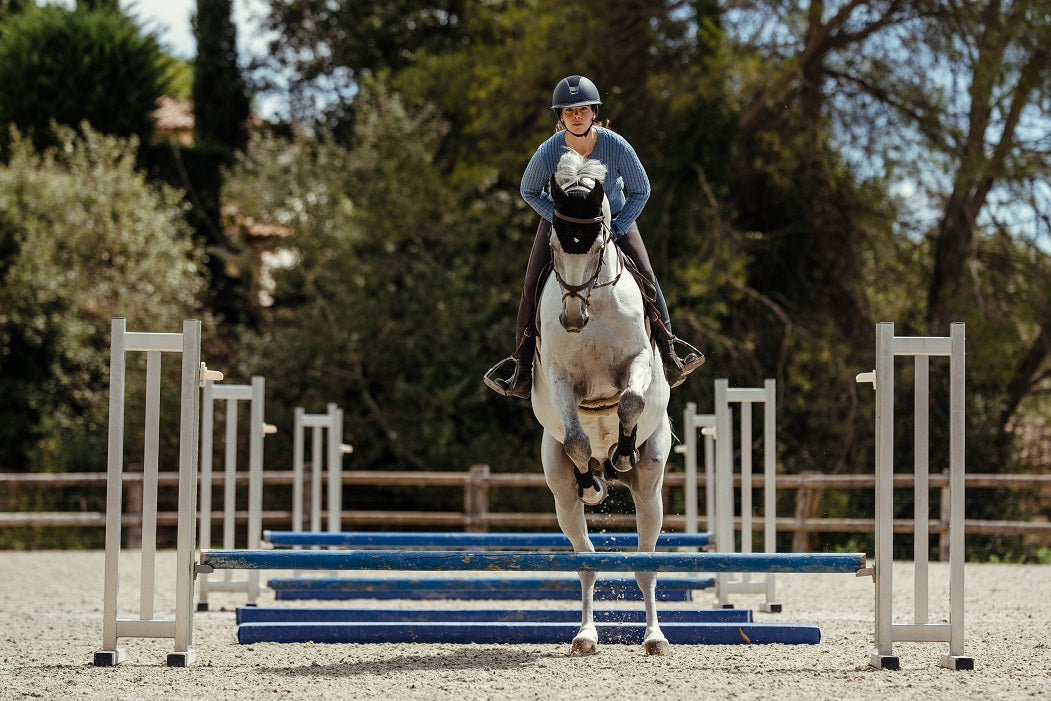 Person riding a horse over jumps in an outdoor equestrian setting
