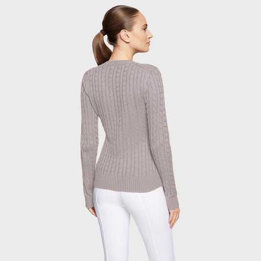 Woman wearing a gray ribbed sweater and white pants on a light gray background