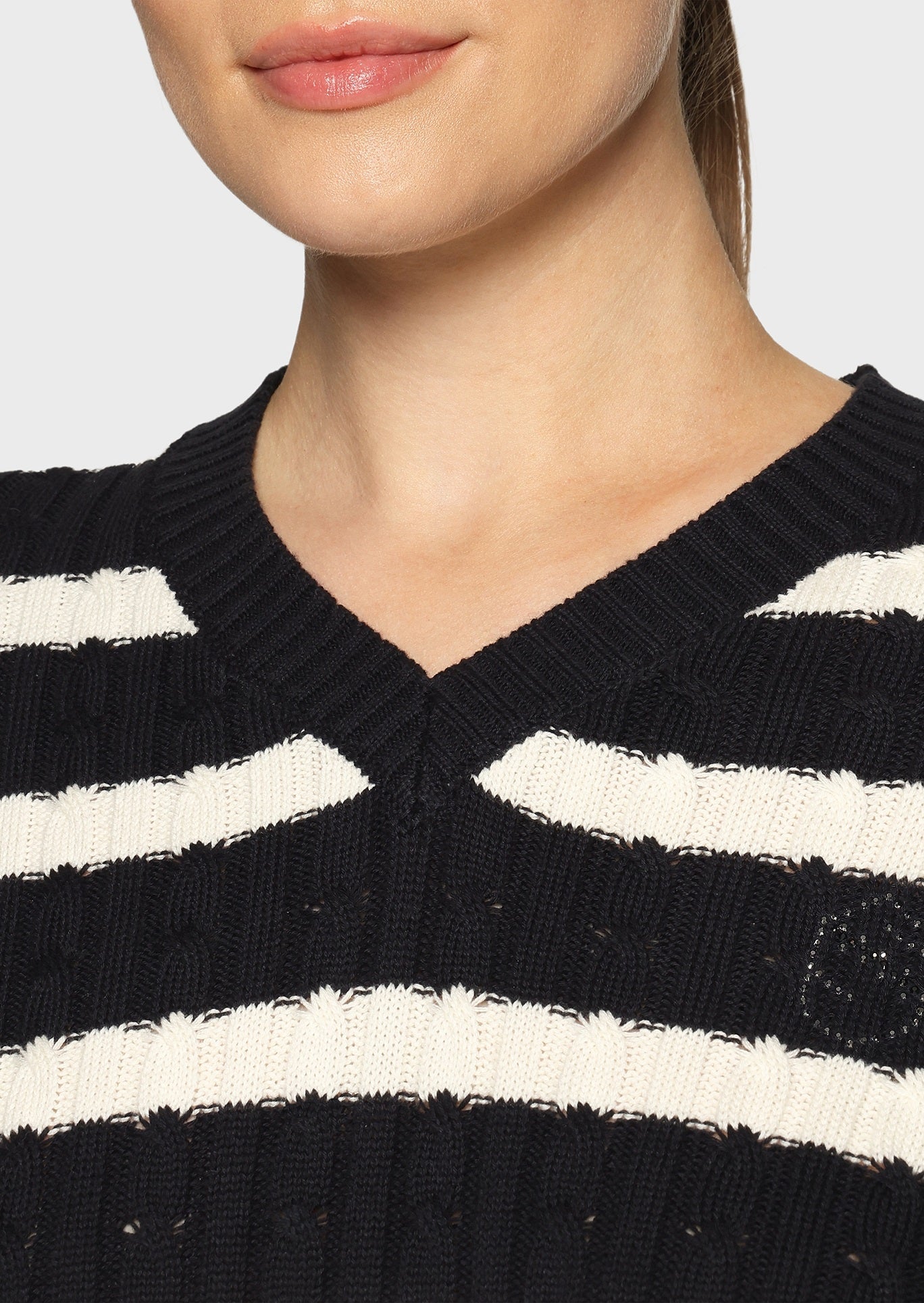 Woman wearing a white and navy striped jumper on a beige background