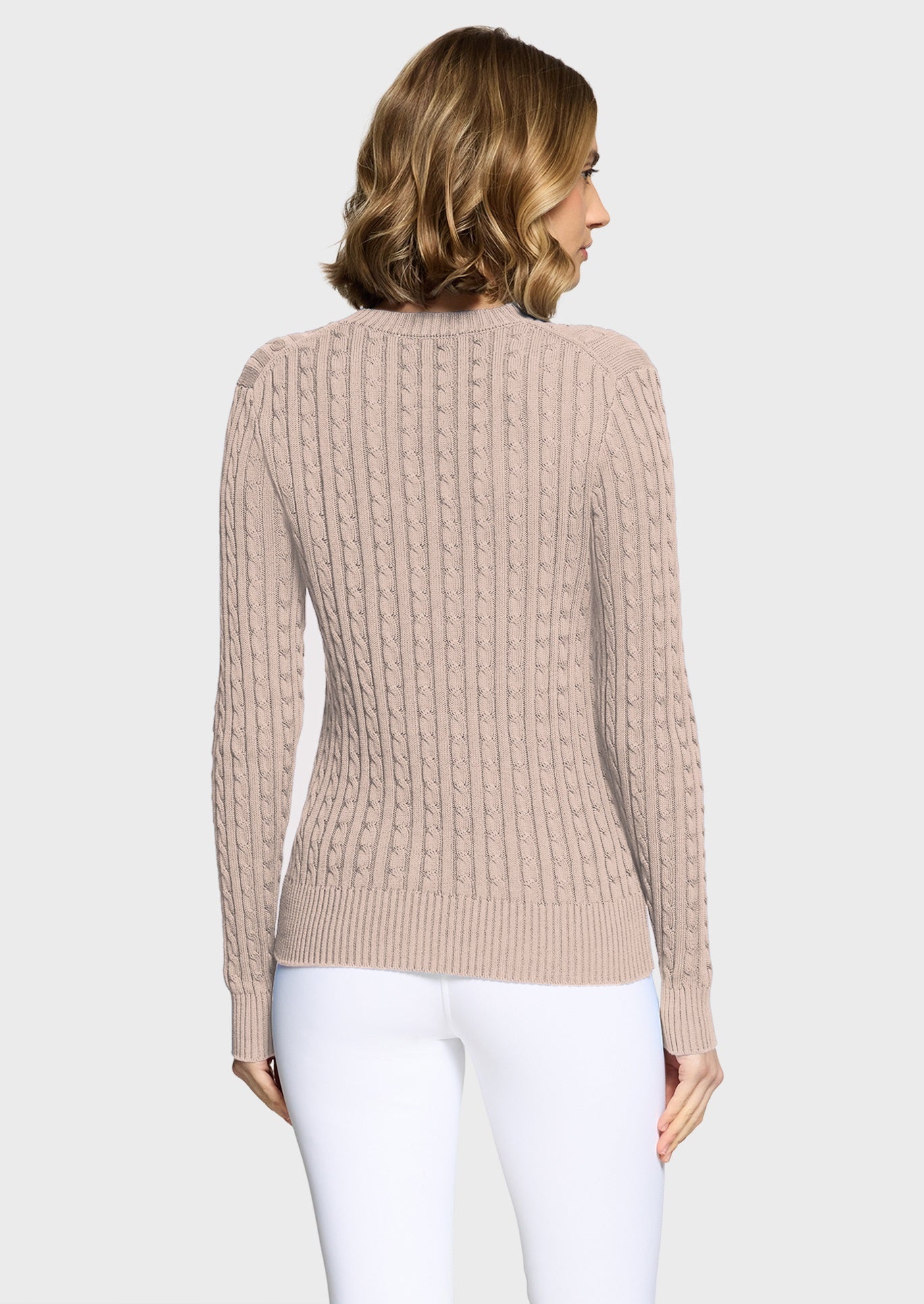 Woman wearing a pink jumper and white breeches on a beige background