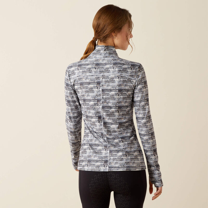 Woman wearing a patterned long-sleeve shirt against a beige background