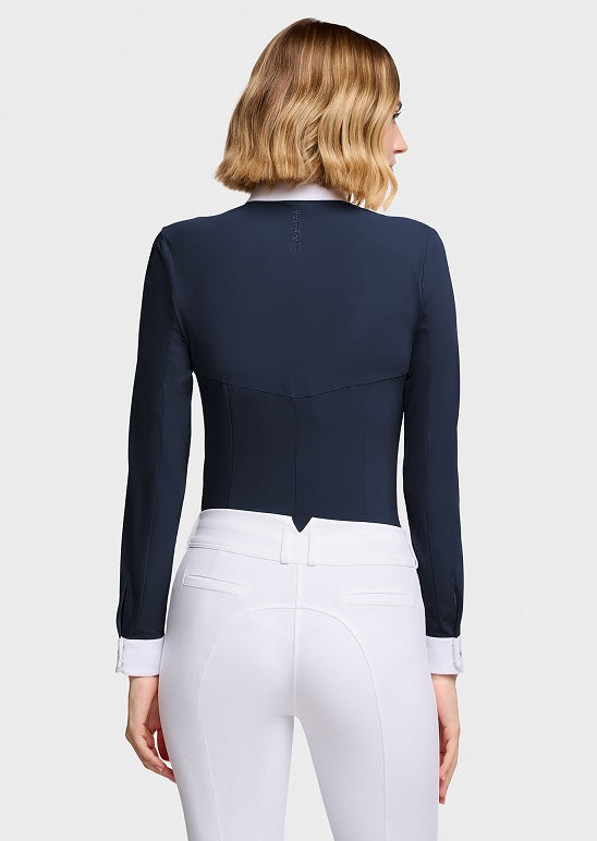 A woman shown from the back wearing a fitted navy long-sleeve cropped equestrian-style top with white riding pants, against a light gray studio background.