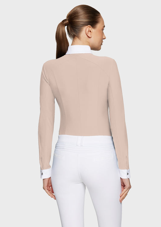 Woman wearing a pink competition shirt and white breeches on a beige background