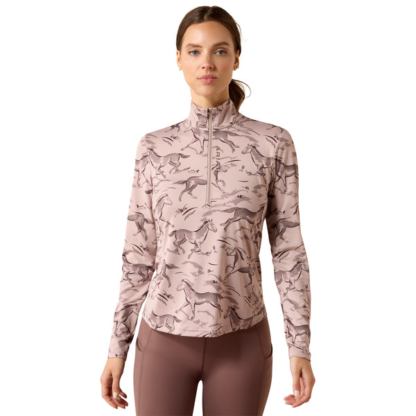 A woman modeling a long-sleeve quarter-zip athletic top with an allover horse pattern in dusty pink and taupe, paired with mauve leggings, against a plain white background.
