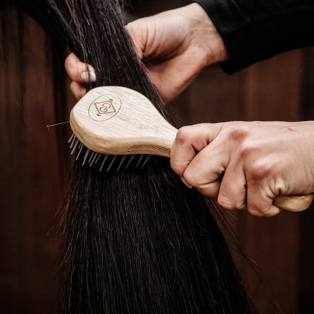 Person using a wooden brush on horse hair