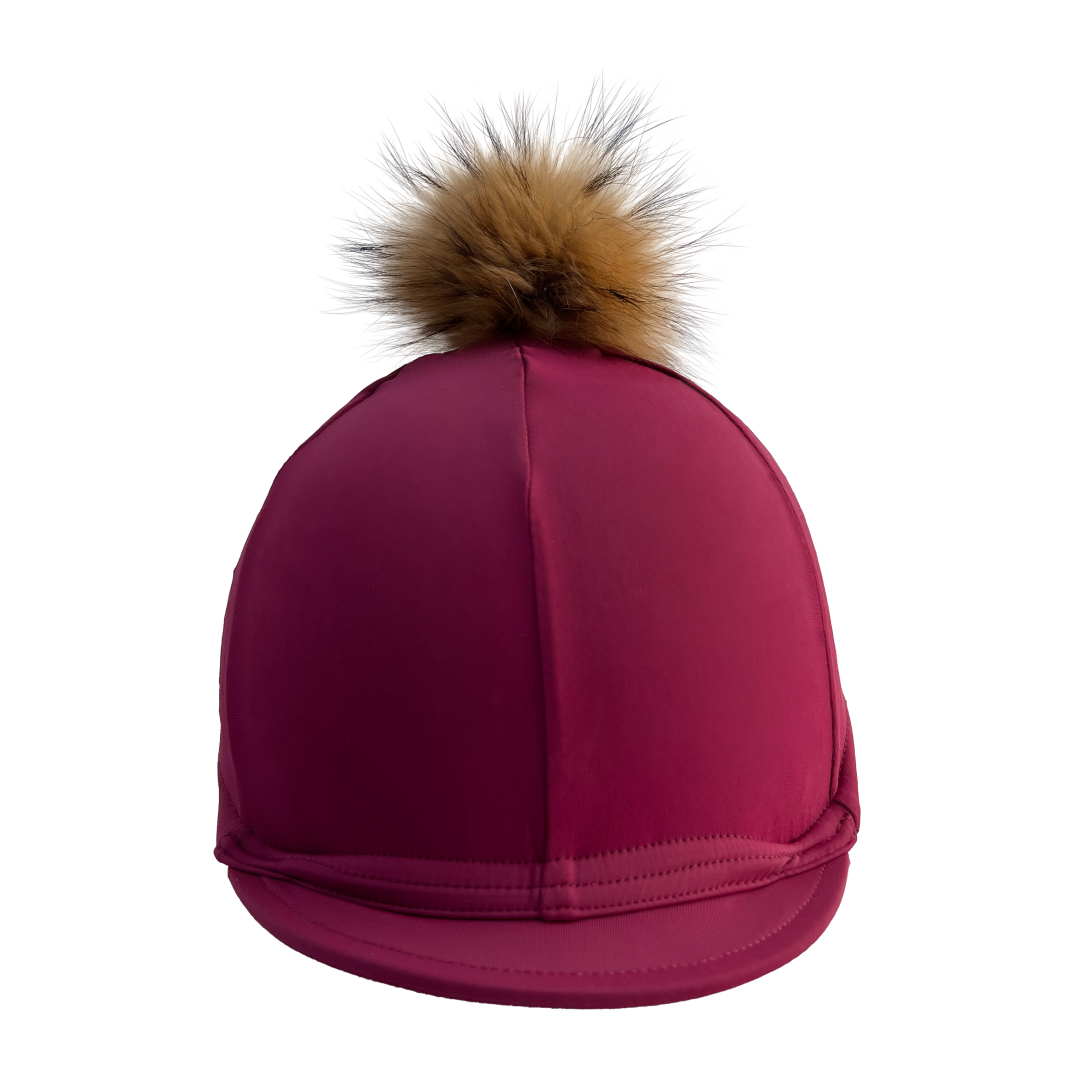 Purple riding helmet with a brown fur pom-pom on a white background