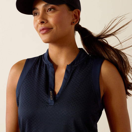Woman wearing a navy sleeveless top with a logo, looking to the side against a beige background