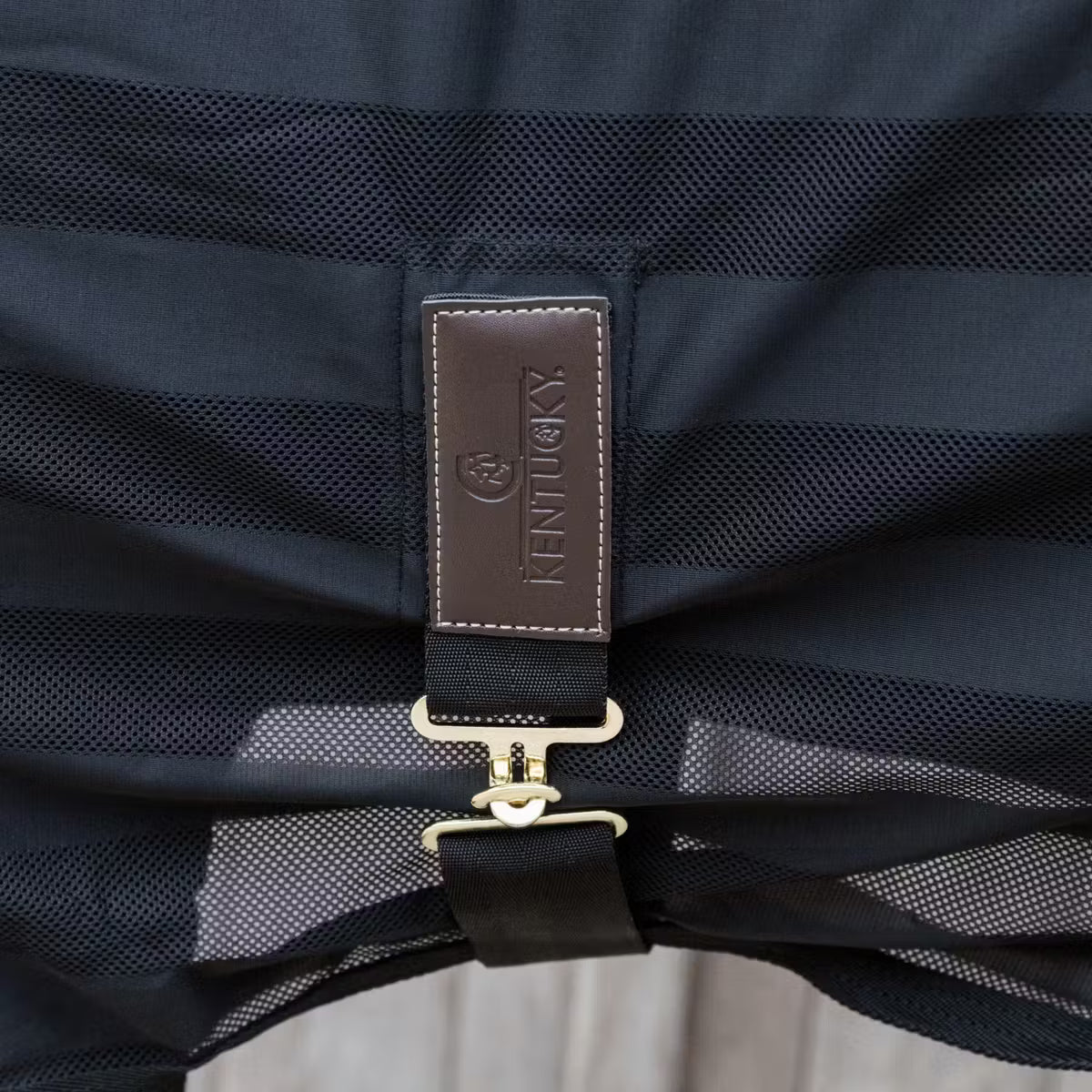 Close-up of a black equestrian saddle with a visible brand logo on the strap.