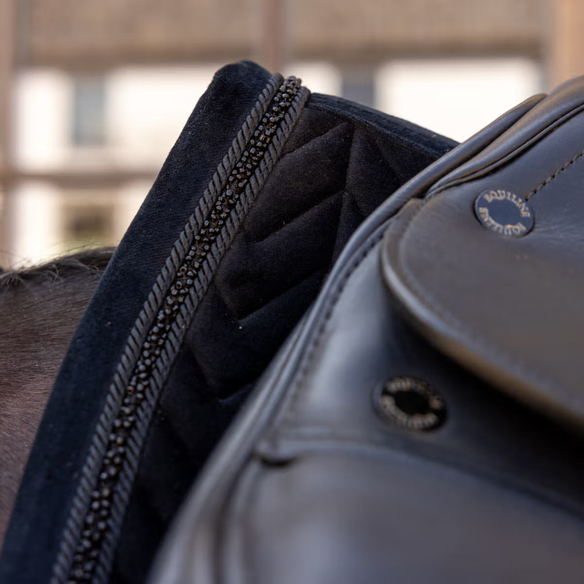 Close-up of a black saddle with a black saddle pad underneath