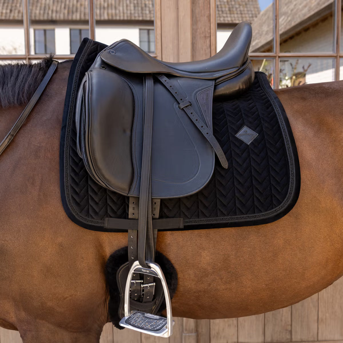 Horse with a black saddle on a wooden stable background