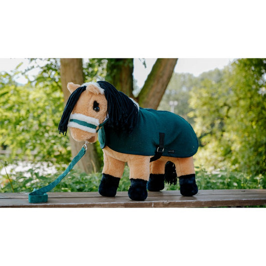 Plush horse toy with a green blanket on a wooden surface with a natural background