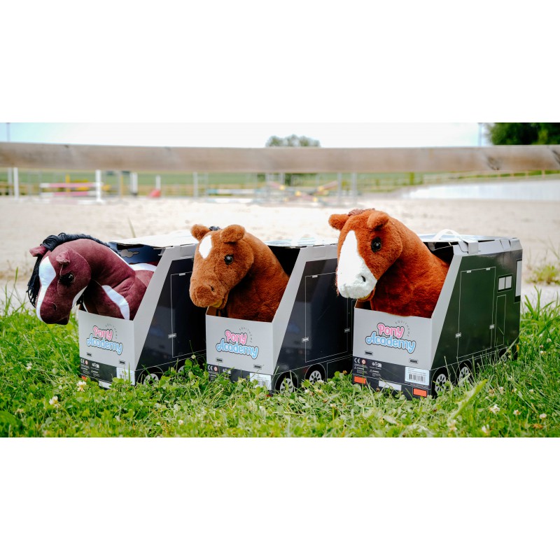 Three plush toy horses in a row with trailers on a grassy field.