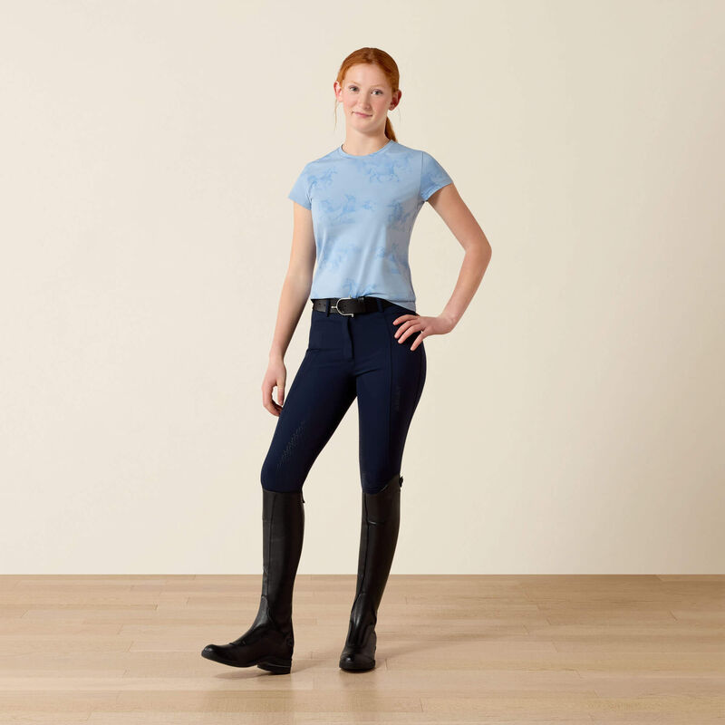 Person wearing a light blue top, dark blue riding pants, and black riding boots on a beige background