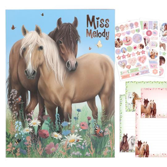 Product packaging with two horses and 'Miss Melody' branding, surrounded by additional horse-themed items.