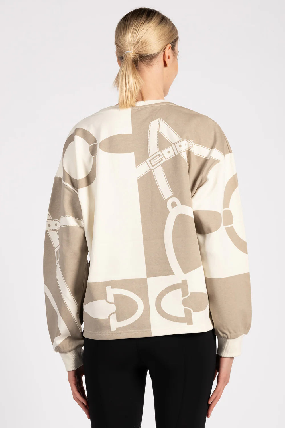 Woman wearing a beige sweater with equestrian motif on a white background