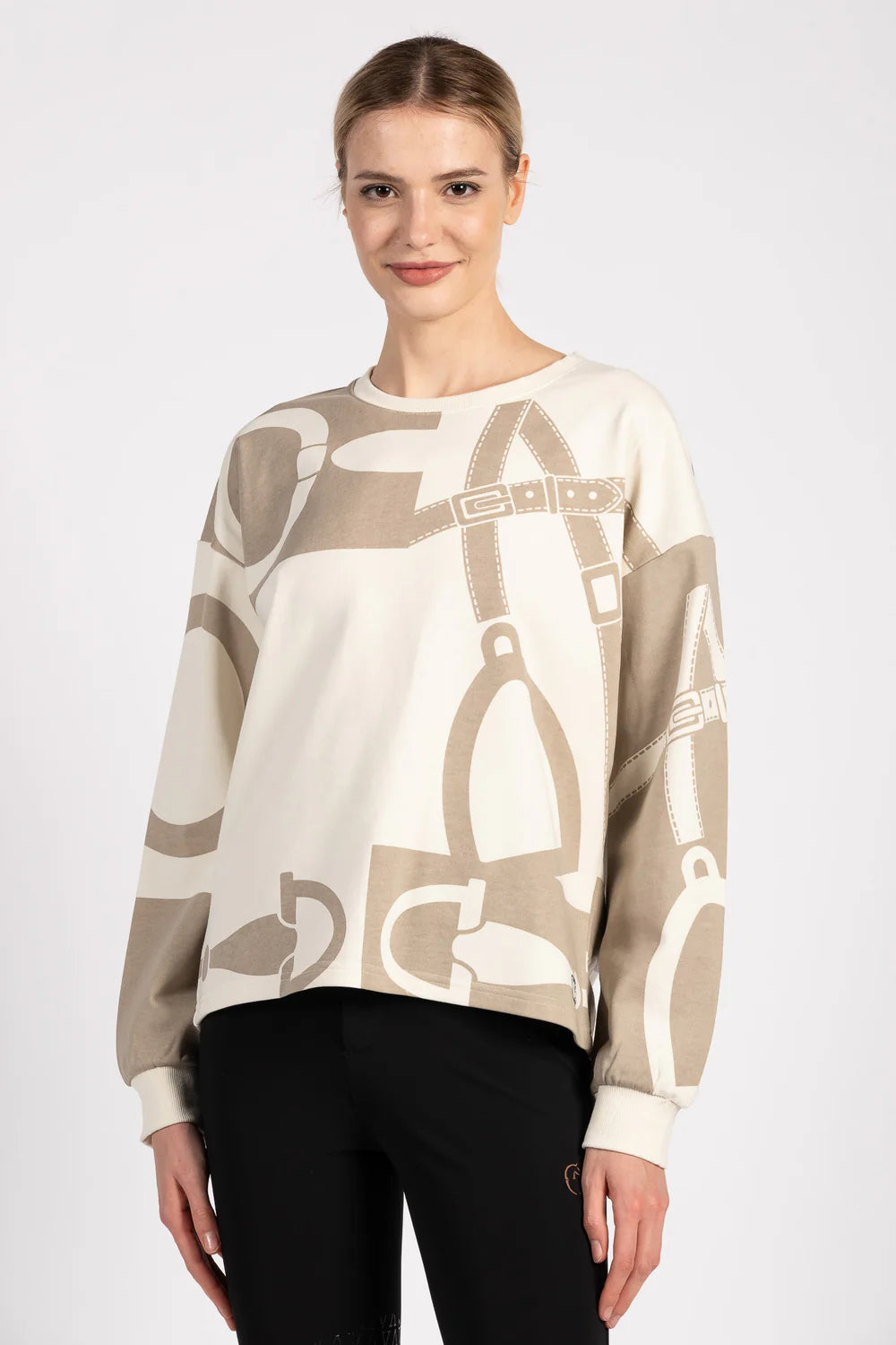 Woman wearing a beige sweater with equestrian motif on a white background