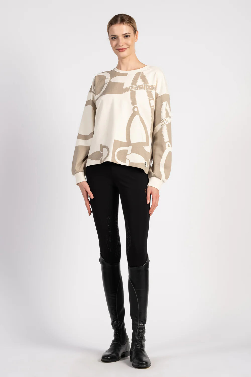 Woman wearing a beige sweater with equestrian motif on a white background