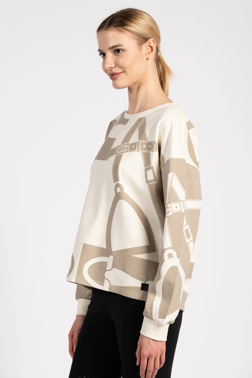 Woman wearing a beige sweater with equestrian motif on a white background