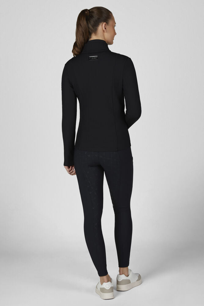 A woman is shown from the back wearing a black long-sleeve mock-neck athletic top and matching black leggings, paired with white sneakers, against a light gray studio background.