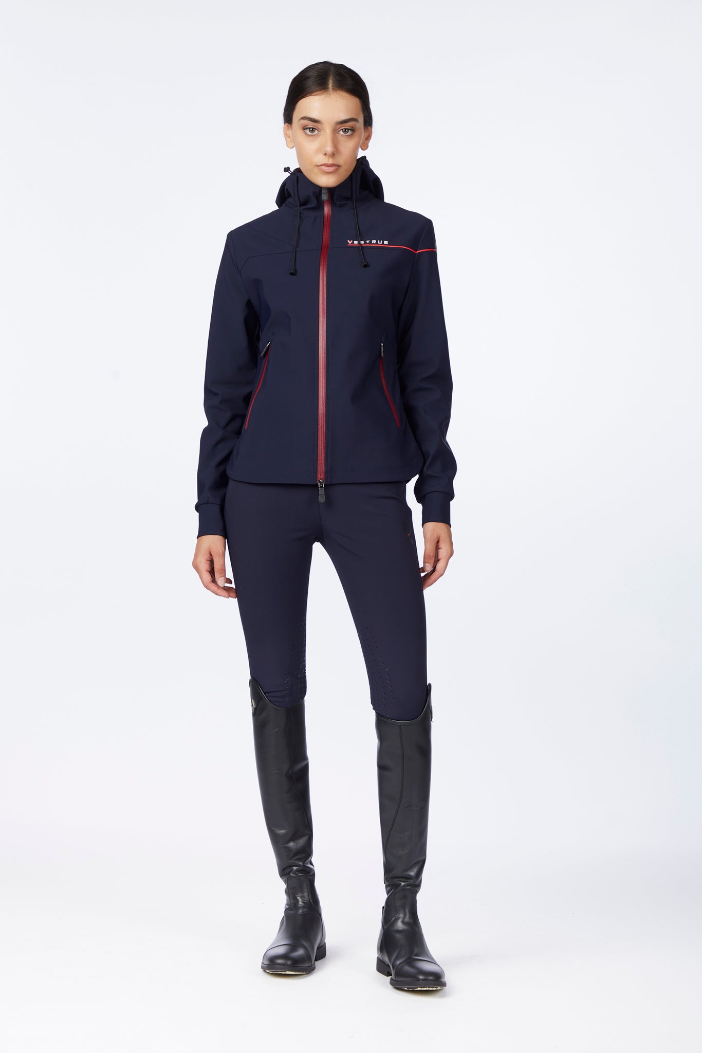 Woman wearing a navy equestrian outfit with a jacket and pants on a white background