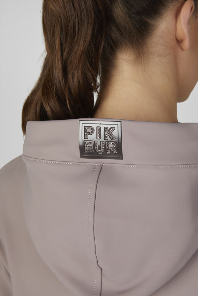 Close-up back view of a person wearing a light taupe hooded top, showing a square metallic brand patch on the collar with the text 'PIK EUR'.
