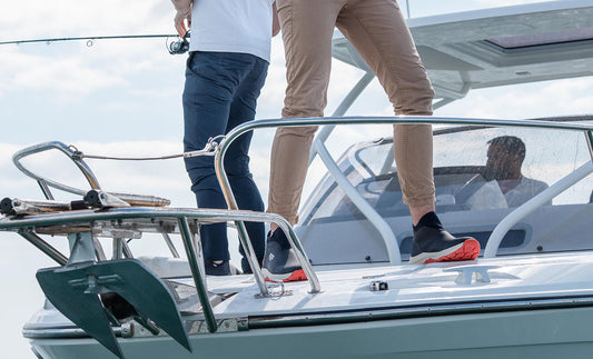 Two people on a boat with one person stepping onto the deck.