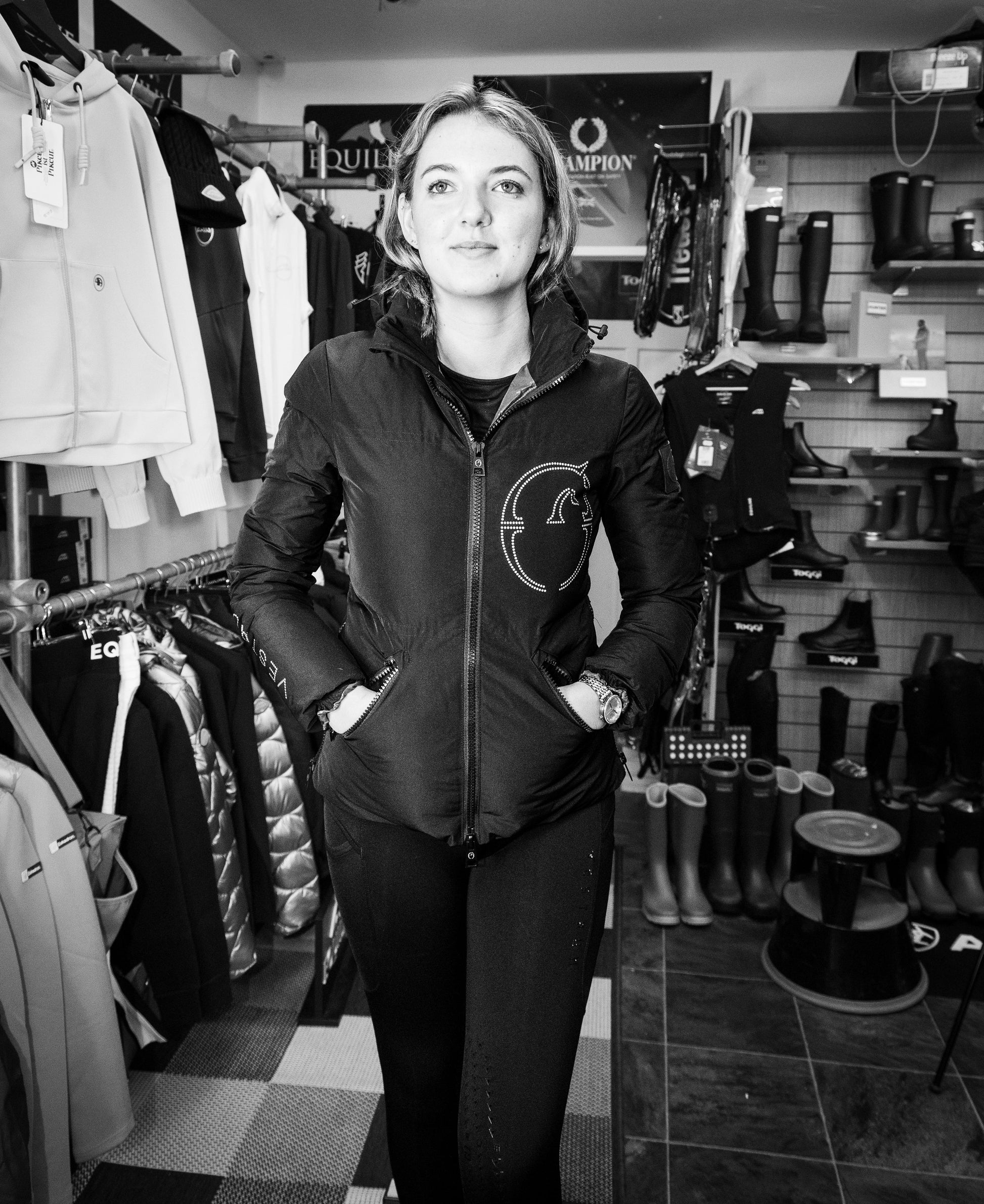 Person wearing a branded jacket in a store with clothing and boots on display