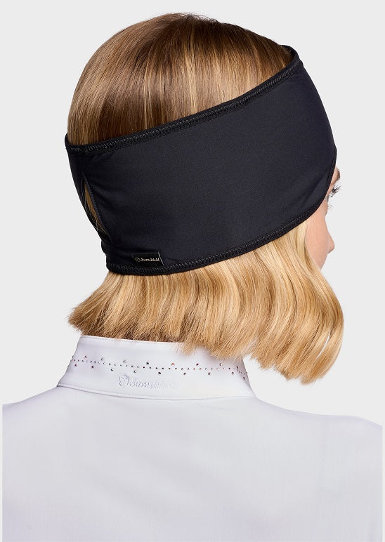 Woman wearing a black athletic headband, set against a light gray background.