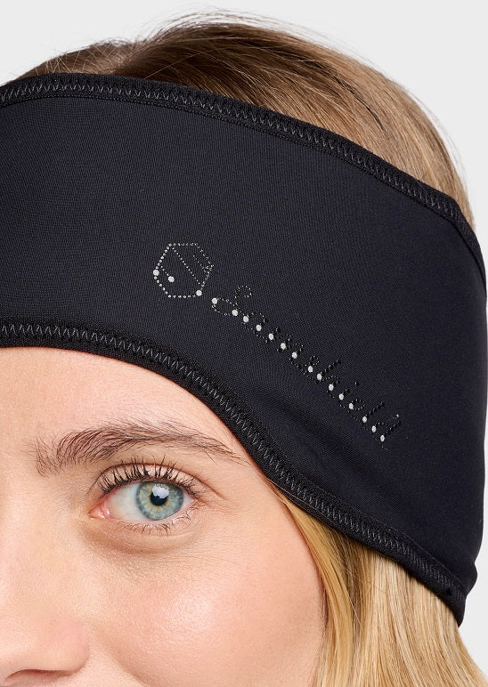 Close-up of a woman wearing a black athletic headband with a white embroidered logo on the side, set against a light gray background.