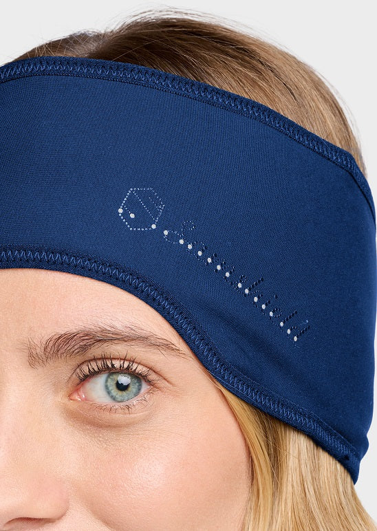 A close-up of a woman wearing a navy blue athletic headband with a white dotted key graphic on the side, set against a light gray background.