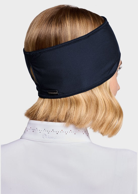 A woman shown from the back wearing a wide, dark navy blue fabric headband. The headband is displayed on her light brown hair, which is styled with a white high-neck collar.