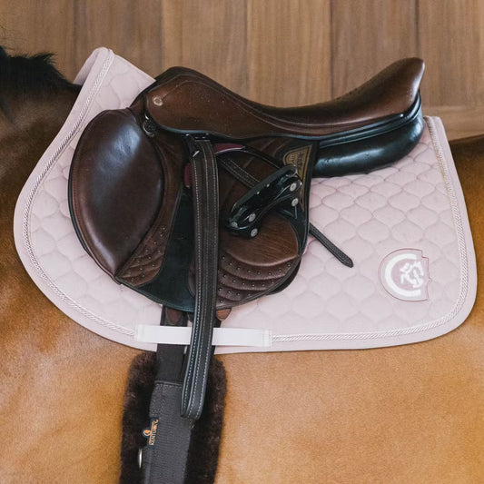 Brown saddle on a horse with a pink quilted saddle pad
